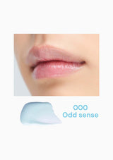 Close-up of lips with a small amount of blue lip balm labeled '000 Odd sense' on a white background.