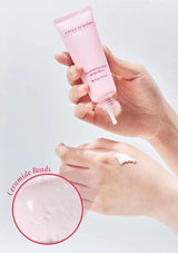 Hand holding a pink skincare tube labeled 'every routine' with a close-up of ceramide beads on a light background.