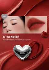 Lipstick with a silver heart-shaped cap, close-up of lips wearing the lipstick, and product name '15 Posy Brick' on a white background.