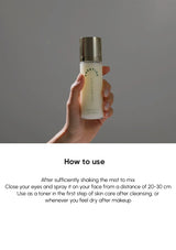 Hand holding a skincare bottle with usage instructions on a gray background