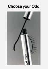 Mascara with false eyelashes being applied, featuring the brand 'oddtypes' on a gray background.