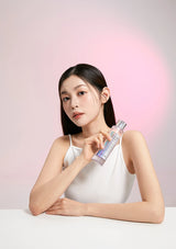 Woman holding a skincare product against a pink background