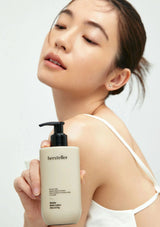 Woman holding a bottle of 'hersteller' body lotion against a light background