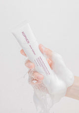 Hand holding a white tube labeled 'Kopher' against a light gray background