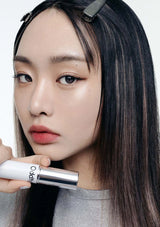 Woman holding a lipstick with a neutral background