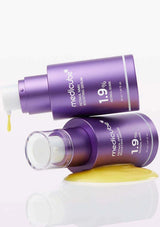 Two purple skincare bottles with a yellow cream on a white background