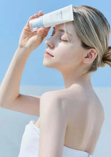 Woman applying sunscreen with a blue sky background