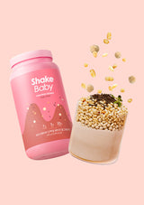 Pink 'Shake Baby' protein shake container with a scoop of protein powder on a pink background