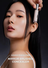 Woman applying concealer with a mirror-brushed concealer bottle on a dark background