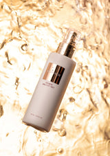 Skincare bottle with gold accents on a water droplet background