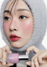 Person wearing a gray hood with a pink cosmetic product in front