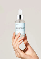 Hand holding a skincare serum bottle labeled 'BUNIKA' against a plain background