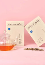 Tea packaging with a teacup and tea leaves on a pink background