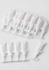 Multiple white skincare tubes with red text on a light gray background