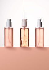 Three skincare bottles with pump dispensers on a peach background