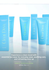 Blue tubes and boxes of Clear Dea. Pure Fit Tinted Sun Lotion arranged on a reflective white surface with promotional text at the bottom.
