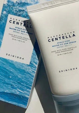 SKIN1004 Madagascar Centella Hyaluronic Water Fit Sun Serum packaging and tube on a gray surface.