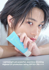 A close-up lifestyle shot of a young man resting his head on his arms, holding a light blue tube of Clear Doll sunscreen. Text at the bottom reads: 'Lightweight yet powerful, seamless blocking Highest UV protection rating SPF50+ PA++++'.