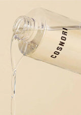 Clear bottle with beige liquid being poured, labeled 'Cosnori', on a beige background