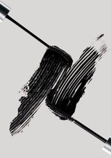 Black mascara wand with smudge on a light gray background