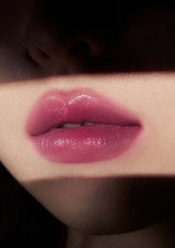 Close-up of glossy pink lips with a dark background