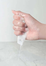 Hand squeezing a clear gel-like substance against a white background