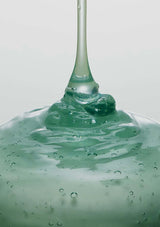 Green liquid being dripped onto a surface with a white background