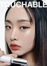 Close-up of a person holding a lipstick with 'TOUCHABLE' branding.