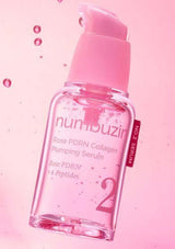Pink skincare serum bottle with droplets on a pink background