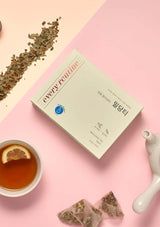 Tea packaging with tea leaves and a cup of tea on a pink background