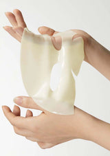 White silicone cupping device held between two hands against a white background