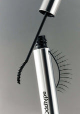 Mascara wand with false eyelashes on a gray background