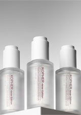 Three Kopher skincare bottles on a gray background