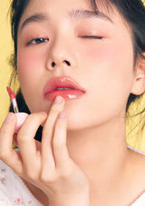Close-up of a person applying lipstick with a yellow background