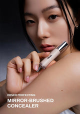 Person holding a concealer with 'Chanel' branding, against a dark background