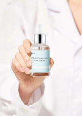 Hand holding a bottle of 'NIA' serum with a blurred background