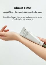 Person applying a tube of 'About Time' fragrance on their arm with product description text above.