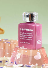 Pink lip potion bottle with decorative stand on a light green background