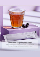 Glass of amber liquid with blackberries and collagen powder packets on a purple surface