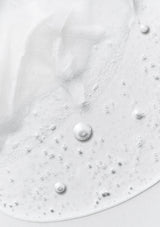 Close-up of white cream with pearl-like beads on a light gray background