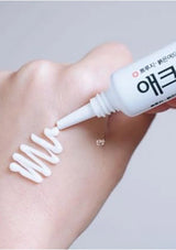 Hand applying white cream to a wrist with a visible brand name.