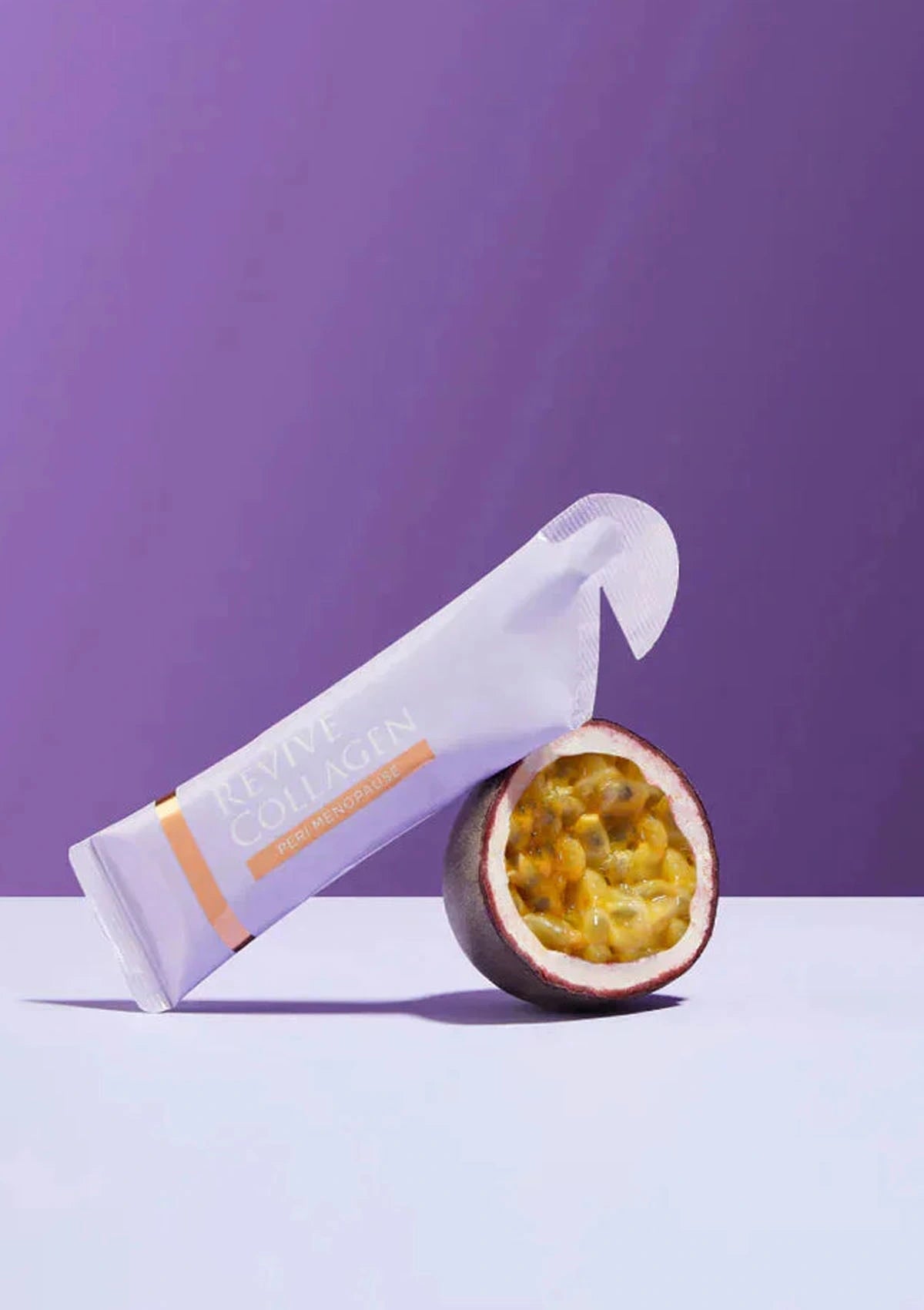 Tube of sunscreen with a halved passion fruit on a purple background