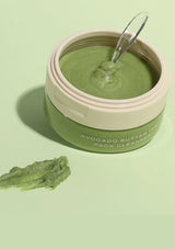 Green facial pack in a jar with a spoon on a light green background
