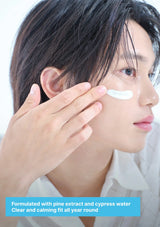 A close-up of a person applying a white eye cream to their cheek, with a blue text banner at the bottom describing the product's ingredients and benefits.