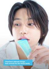 A close-up lifestyle shot of a person holding a light blue tube of ClearDea toothpaste near their mouth, with a text overlay at the bottom.