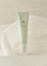 Green tube of skincare product on a soft beige background
