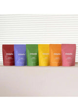 Six Odada coffee bags in different colors on a white surface with a white background