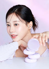 Woman with a stack of purple cosmetic products on a white background