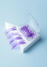 Purple contact lenses in a clear plastic case on a light blue background