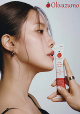 Woman holding a tube of Olivazumo product against a plain background